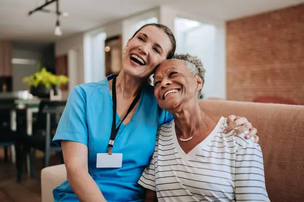 nurse and elderly woman laughing and hugging