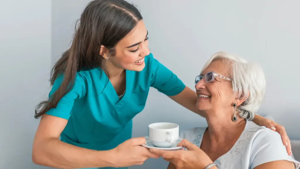in-home care giver giving elderly person coffee